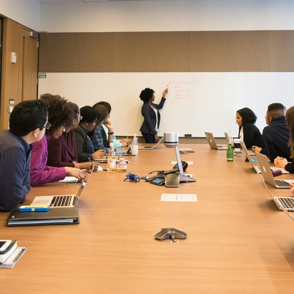 Team in a boardroom listening to a presenter at the whiteboard