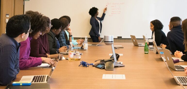 Team in a boardroom listening to a presenter at the whiteboard