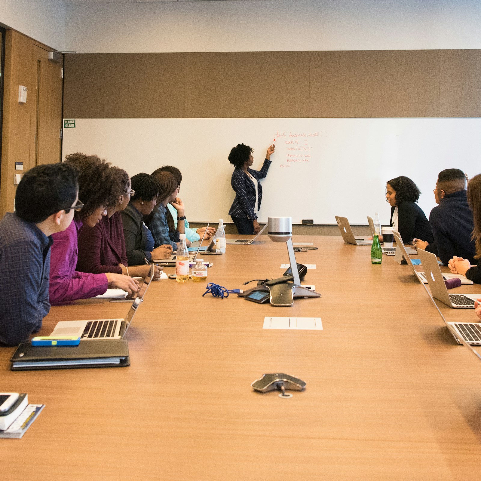 Team in a boardroom listening to a presenter at the whiteboard