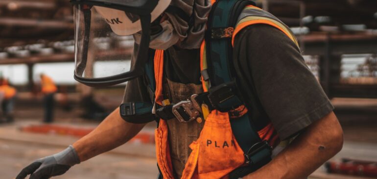 Construction worker in safety gear measuring lumber on a job site