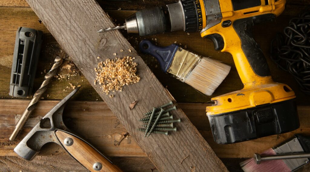 Hammer and cordless drill on a wooden work bench