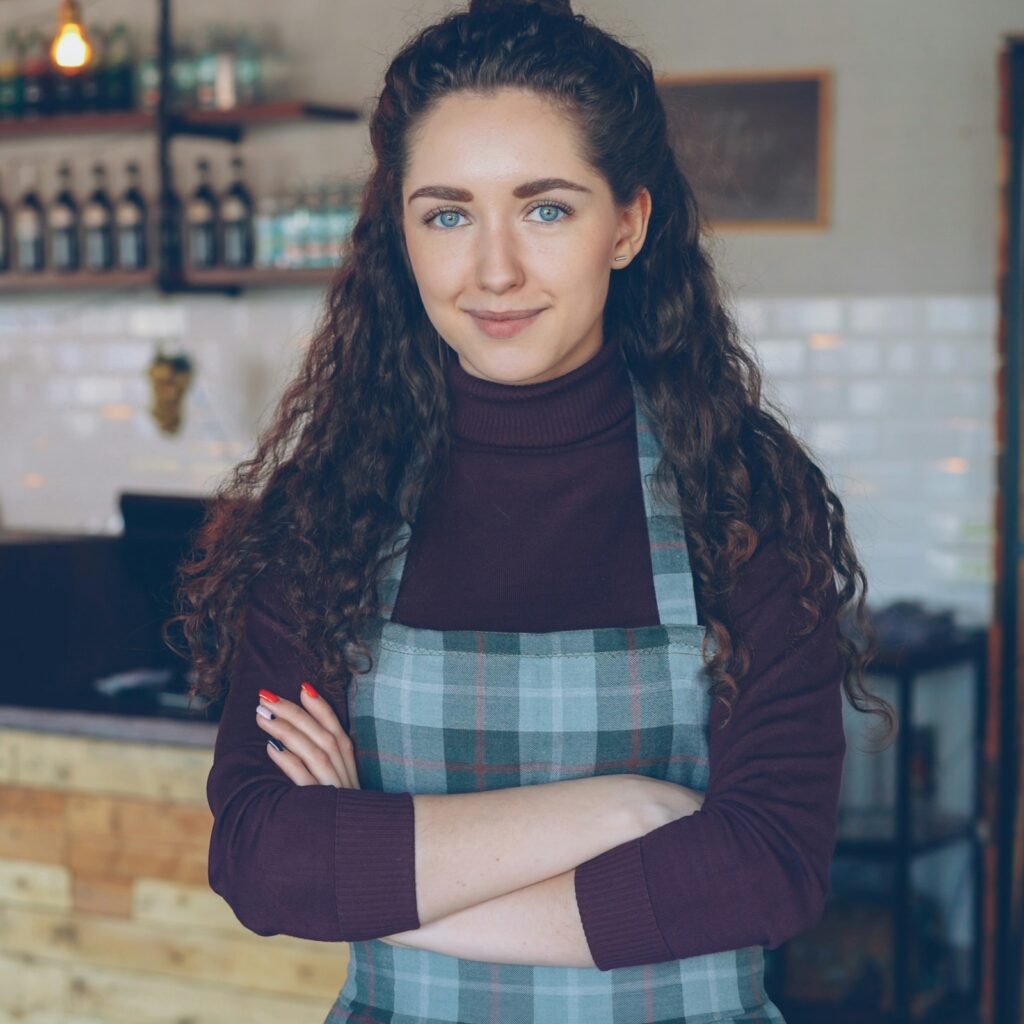 Small business owner standing at the counter of her coffee shop
