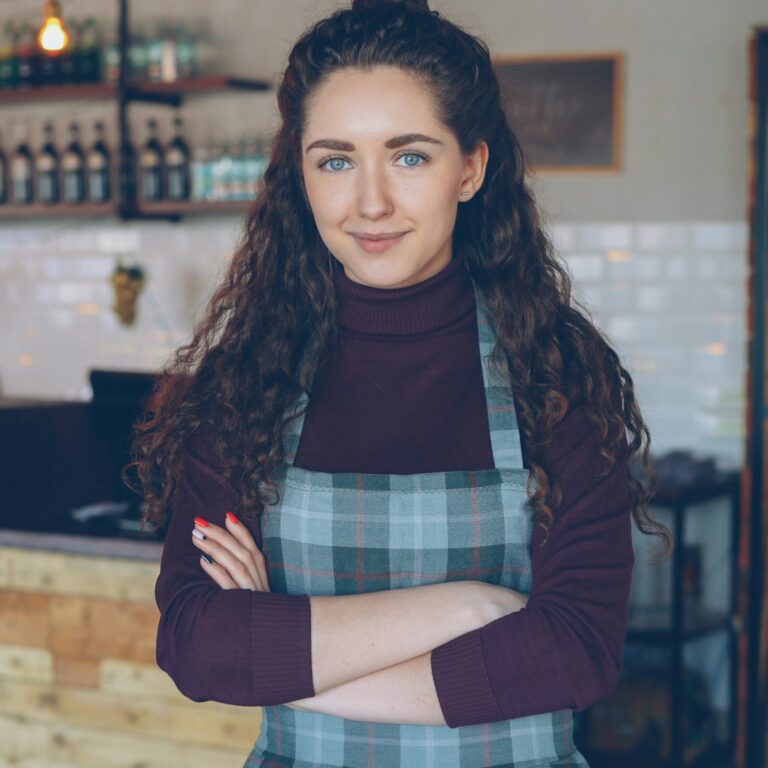 Small business owner standing at the counter of her coffee shop