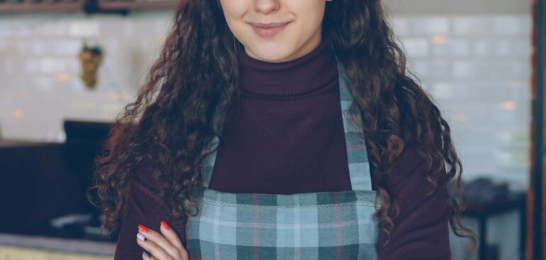 Small business owner standing at the counter of her coffee shop