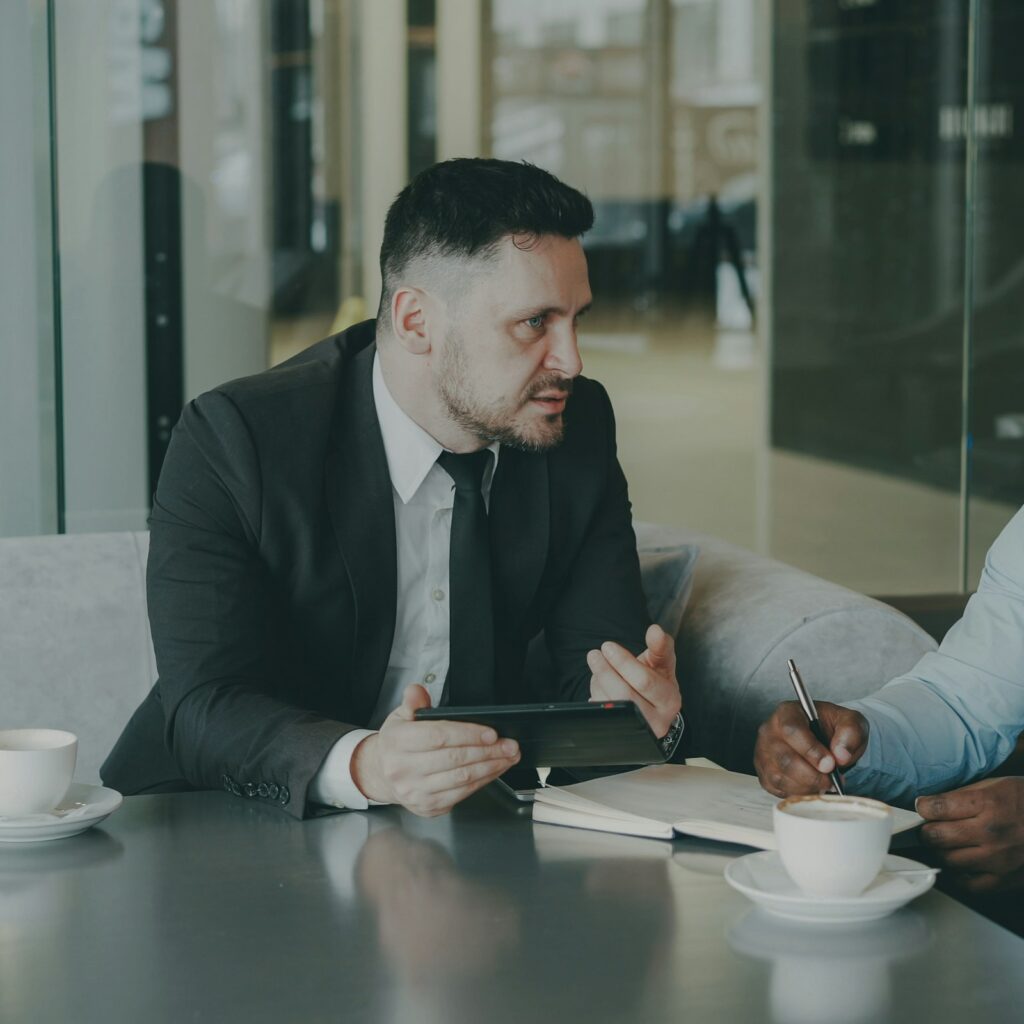Two business partners reviewing a contract at a cafe table with a laptop