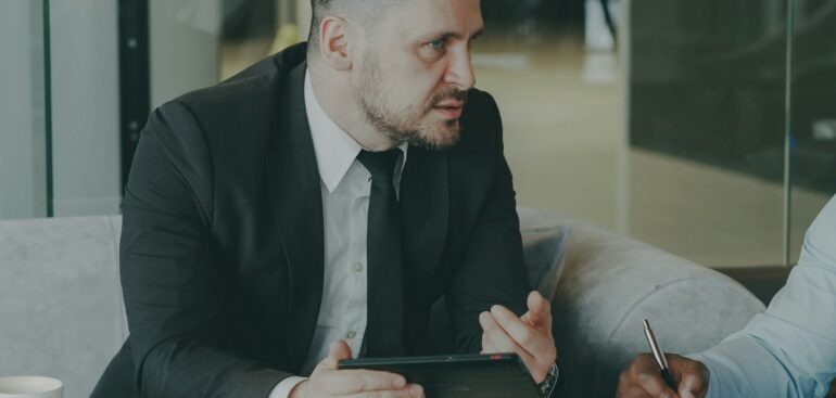 Two business partners reviewing a contract at a cafe table with a laptop