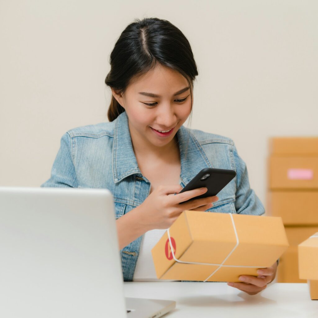 Online store owner checking a package beside a laptop and shipping boxes