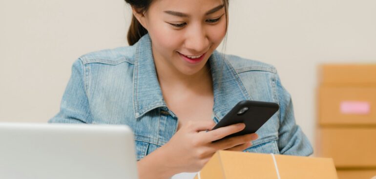 Online store owner checking a package beside a laptop and shipping boxes