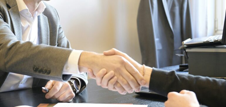 Business owner shaking hands with a new bookkeeper across a desk