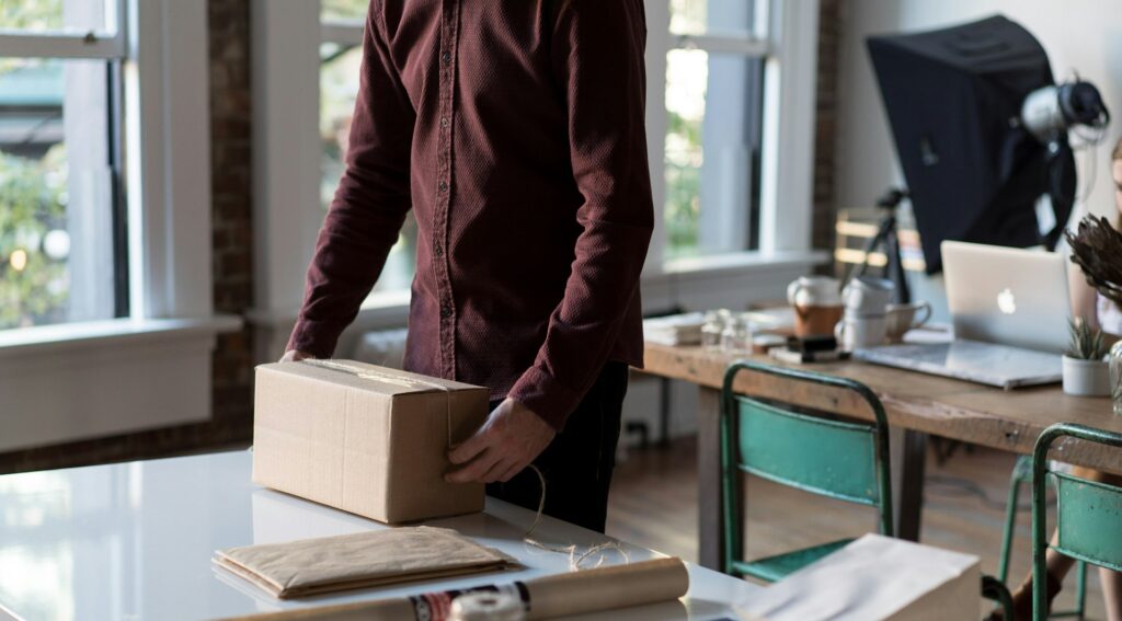 Ecommerce seller packing an order box at a workspace