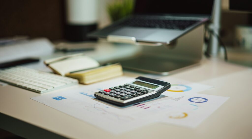 Office desk with a calculator, notebook and printed financial charts